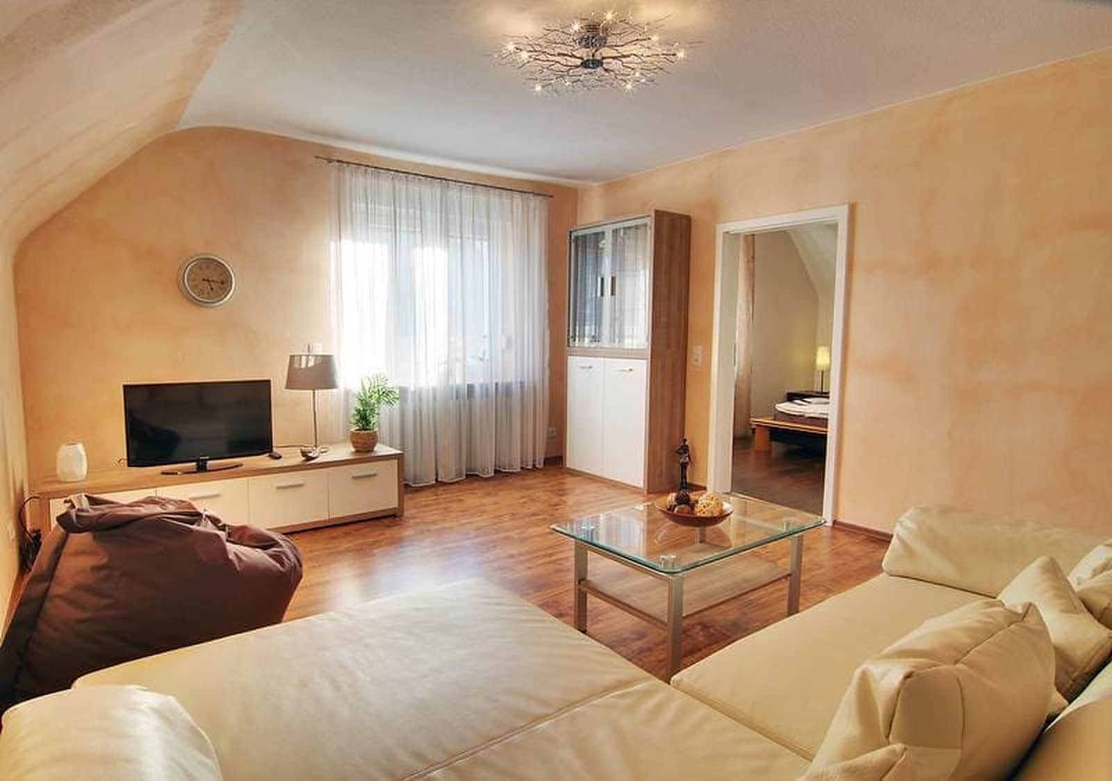 A living room with a sofa, a glass coffee table, a television, and a plant.