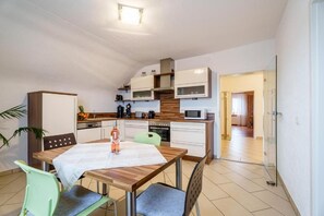 Una cocina moderna con armarios blancos, microondas y un comedor con mesa y sillas.