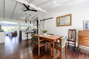 A spacious dining area with a wooden table and chairs, a ceiling fan, and a large mirror on the wall.