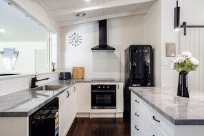 A modern kitchen with white cabinetry, a black stove, and a refrigerator.
