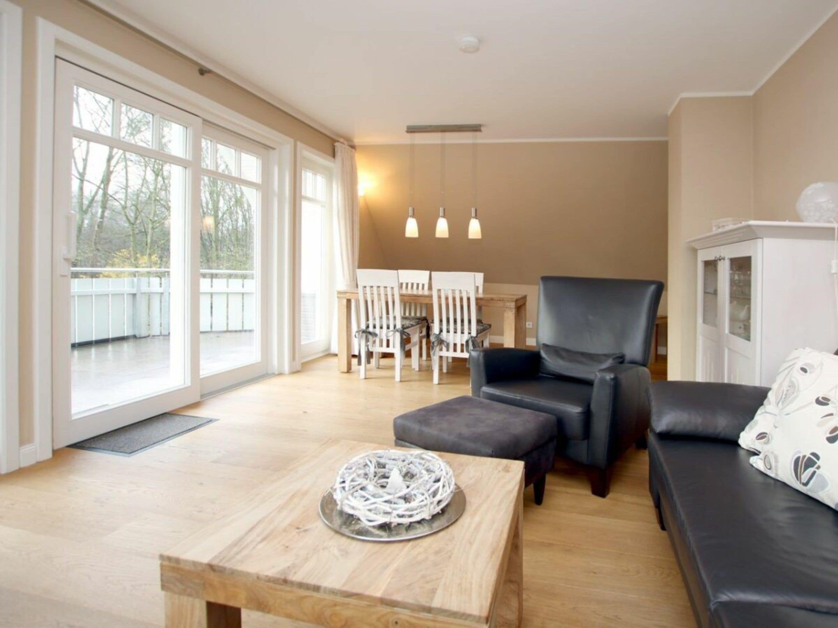 Una sala moderna con sofá, sillón, mesa de comedor y un amplio ventanal.