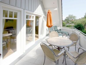 Eine überdachte Terrasse mit Tisch und Stühlen, eine Glastür und ein Sonnenschirm.