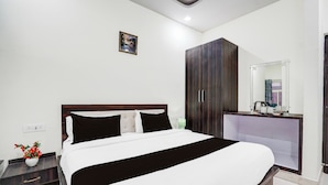 A hotel room with a bed, bedside table, wardrobe, and a mirror. - Townhouse Faizabad Road Opp BBD (Lucknow)