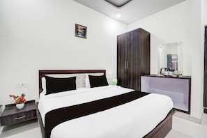 Une chambre d’hôtel comprenant un lit, une table de chevet, une armoire et un miroir.