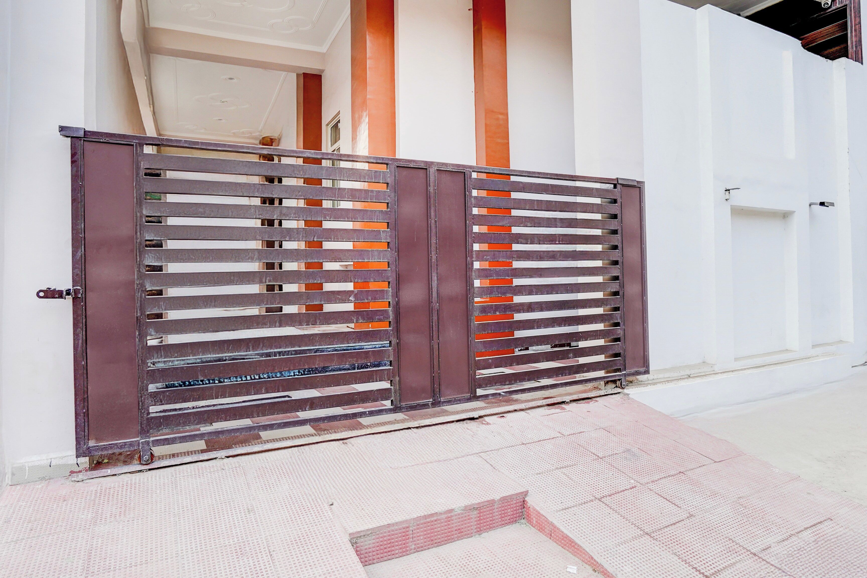 A gated entrance with a metal gate and a white wall.