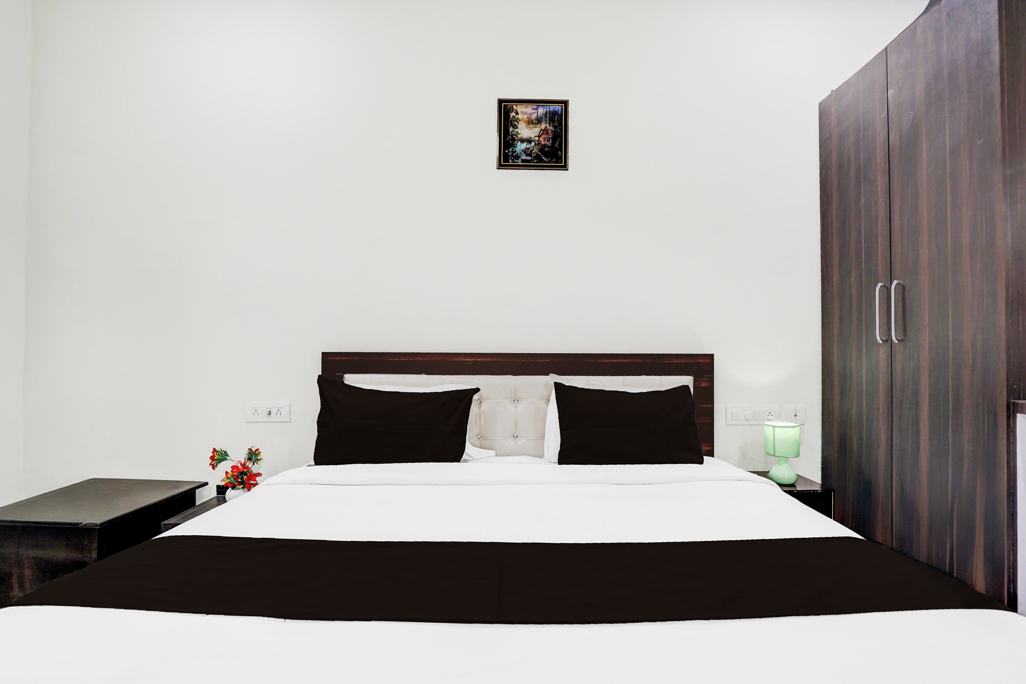 Ein Schlafzimmer mit Bett, Nachttisch, Lampe und Kleiderschrank.