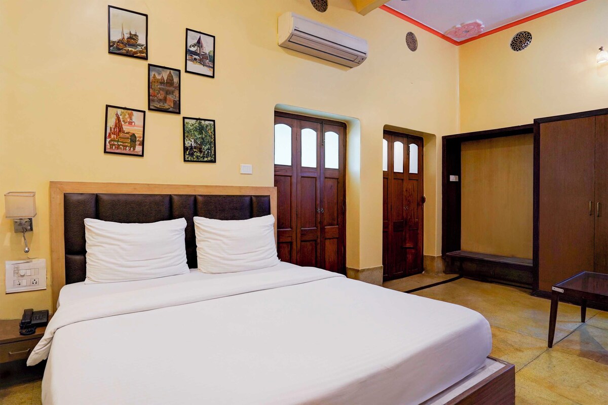 Een hotelkamer met een bed, een bureau, een kledingkast en een muur met ingekaderde foto's.