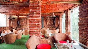 A room with wicker furniture, a glass table, and a red cushion. - Townhouse Oak Varanasi Ganga Ghat (Varanasi)