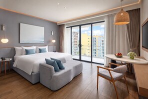 Une chambre d’hôtel moderne dotée d’un grand lit, d’un coin salon, d’une table à manger et offrant une vue sur la ville.