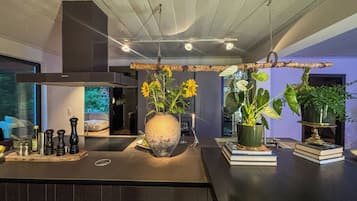 A modern kitchen with a central island, a hanging light fixture, and a view of the outside.