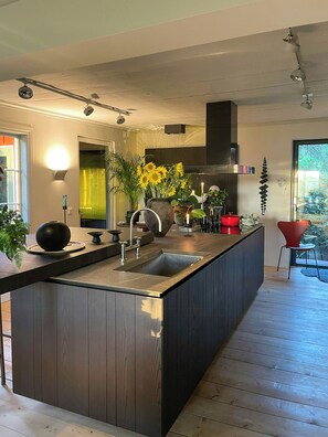 A modern kitchen with a central island, built-in appliances, and a view of the outdoors.