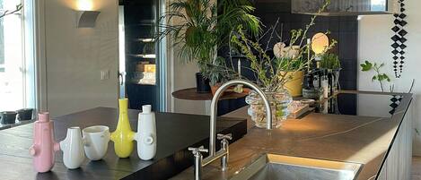 A modern kitchen with a large island, stainless steel sink, and a built-in oven.