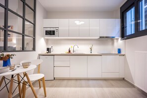 Eine moderne Küche mit weißen Schränken, einer Bosch-Mikrowelle, einem Spülbecken und einem Essbereich mit weißem Tisch und Stühlen.