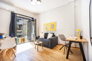 A modern living room with a grey sofa, a wooden coffee table, and a dining area with a yellow lamp. - FiftySeven Athens - Quieter Pace, Balcony | 003 (Athina)