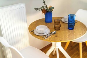 A round wooden table with a white plate, a bowl, and a blue glass. - FiftySeven Athens - Quieter Pace, Balcony | 003 (Athina)