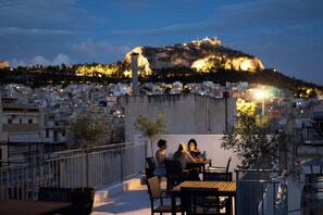 Eine Dachterrasse mit Blick auf eine städtische Landschaft auf einer Anhöhe, einschließlich eines markanten Hügels mit Lichtern.