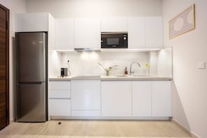 A modern kitchen with a stainless steel refrigerator, a Bosch microwave, and white cabinetry. - FiftySeven Athens - City Pulse, Balcony | 004 (Athina)