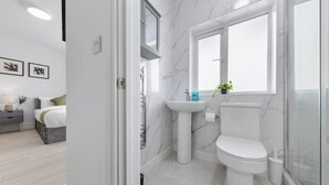 A modern bathroom with a marble sink, toilet, and shower enclosure. - Welcome to our modern and spacious 6-bedroom, all en-suite home in **Northolt, West London**, perfect for **up to 12 guests**. Ideal for business travellers, contractors, families, relocation stays, and group trips. (Greater London)
