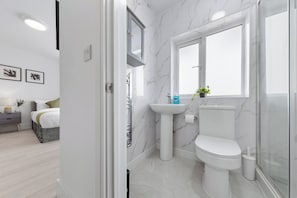 A modern bathroom with a marble sink, toilet, and shower enclosure. - Welcome to our modern and spacious 6-bedroom, all en-suite home in **Northolt, West London**, perfect for **up to 12 guests**. Ideal for business travellers, contractors, families, relocation stays, and group trips. (Greater London)