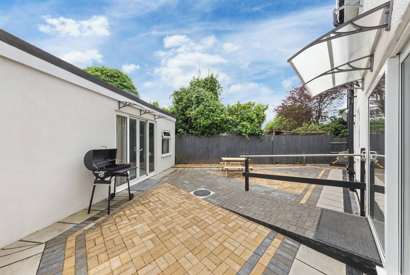 A patio area with a barbecue grill, a picnic table, and a covered seating area.