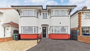 A two-story residential building with a flat roof, a front door, and a driveway leading to a gravel area. - Welcome to our modern and spacious 6-bedroom, all en-suite home in **Northolt, West London**, perfect for **up to 12 guests**. Ideal for business travellers, contractors, families, relocation stays, and group trips. (Greater London)