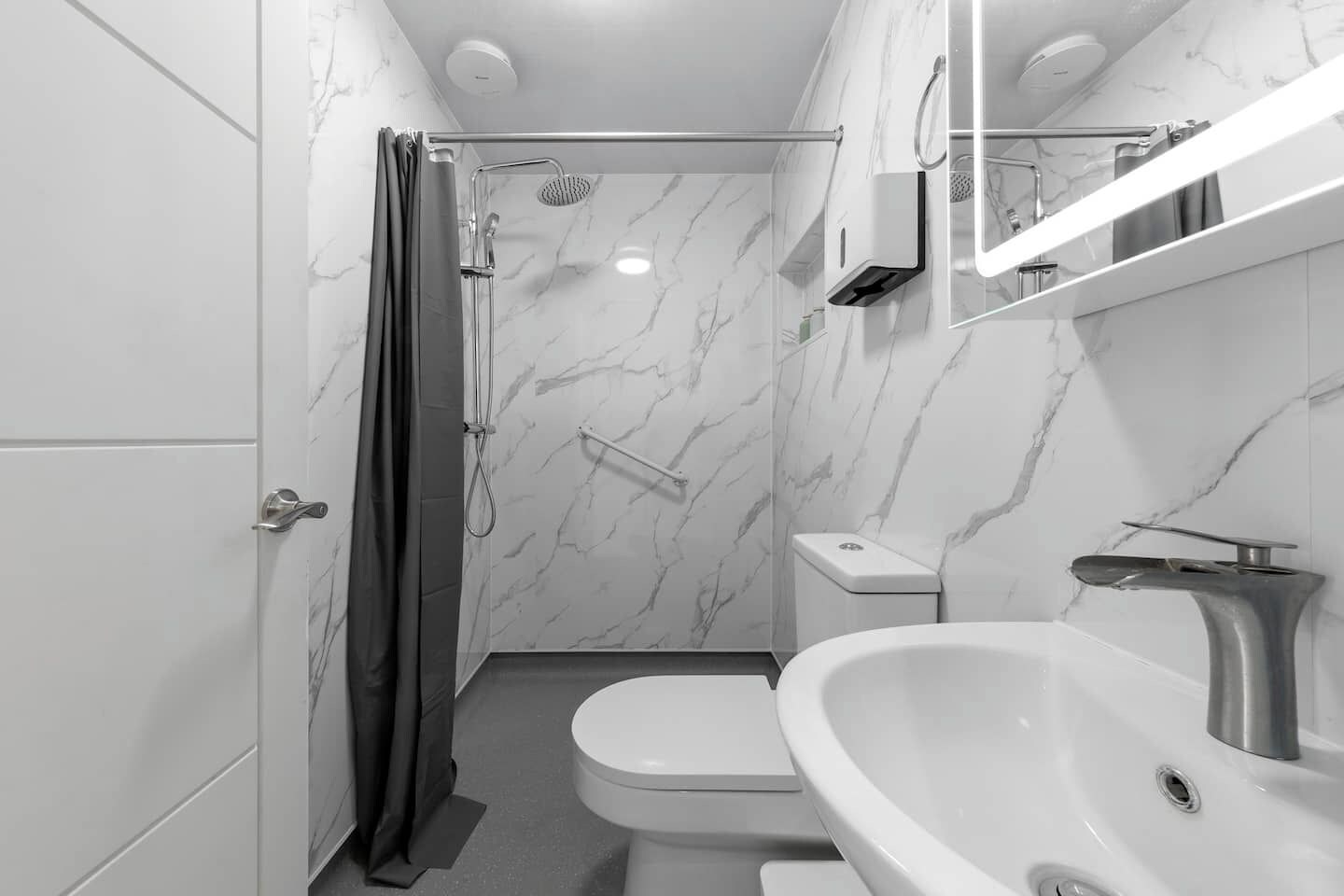 A modern bathroom with a shower, toilet, and sink.