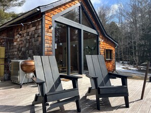 A cabin with a deck, two Adirondack chairs, and a barbecue grill. - The Paradise Cabin w/ Sauna - 10 min to the Falls (Elka Park)