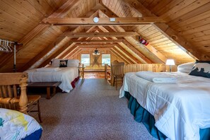 A cozy attic bedroom with two beds, a wooden ceiling, and a view of the outdoors. - Secluded Island Park Cabin with Hot Tub Near Yellowstone & Henrys Lake, Idaho (Island Park)