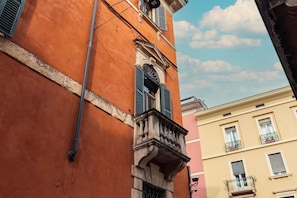 A corner view of a building with a balcony, a window with shutters, and a visible pipe. - Residenza Adua - 150 meters from the Verona Arena (Verona)