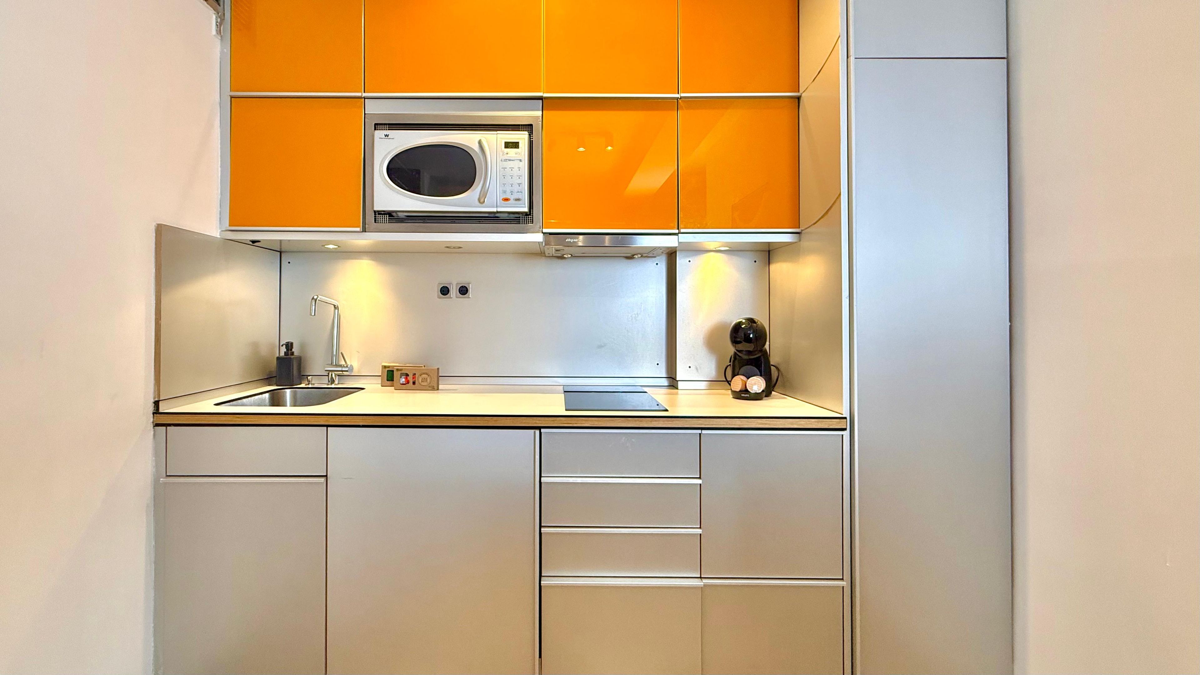 A kitchen with a microwave, sink, and coffee machine.