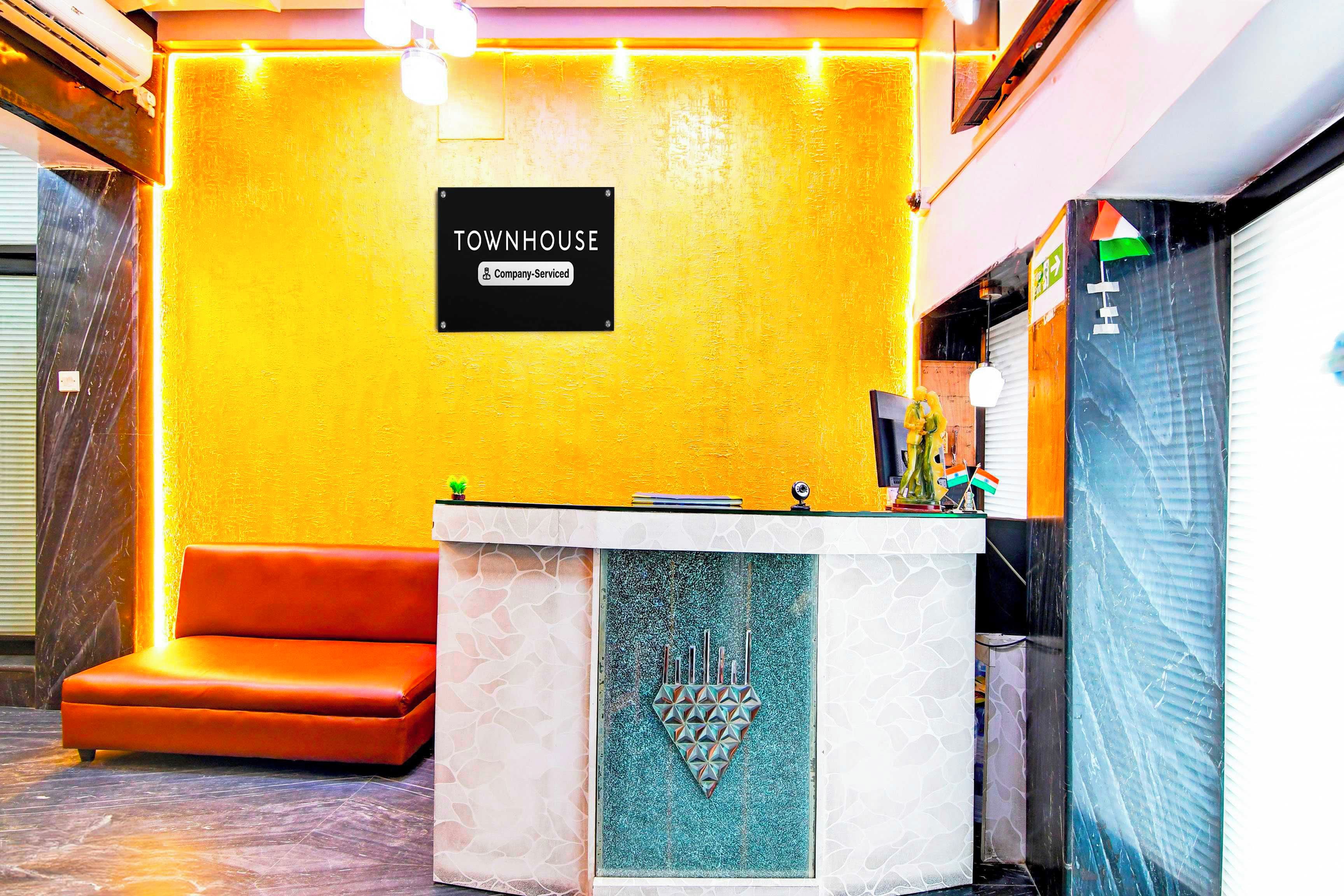 A reception area with a yellow wall, a reception desk, and a brown sofa.