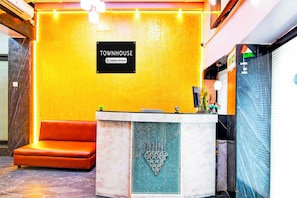 A reception area with a yellow wall, a reception desk, and a brown sofa.