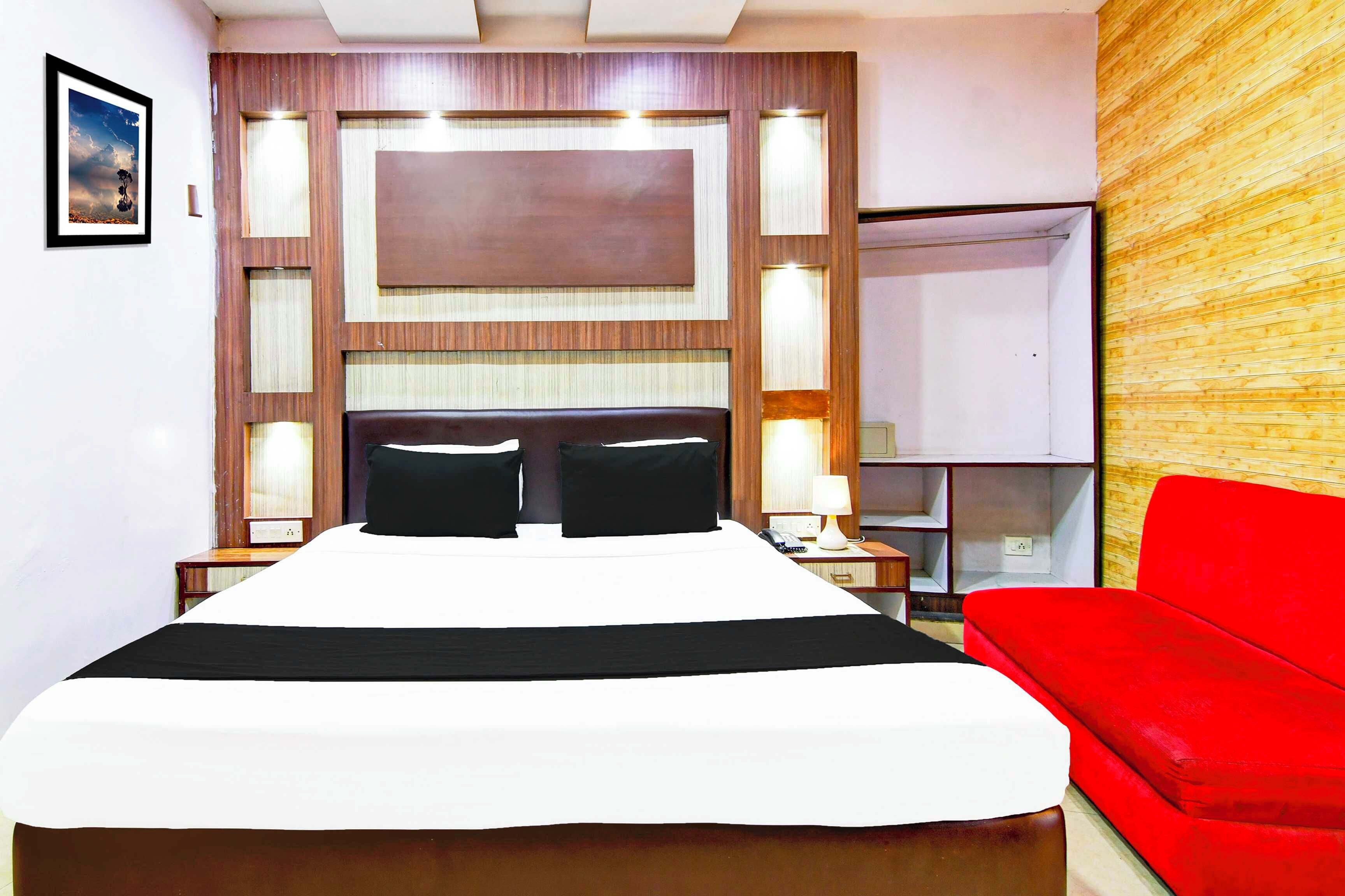 A hotel room with a large bed, a red chair, and a wooden accent wall.