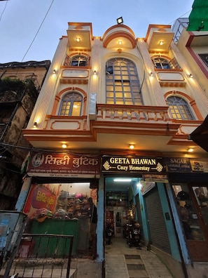 A two-story building with a storefront at the ground level. - Geeta Bhawan Cozy Homestay (Varanasi)