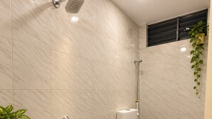 Ein modernes Badezimmer mit Dusche, Toilette und einer kleinen Ablage für Toilettenartikel.