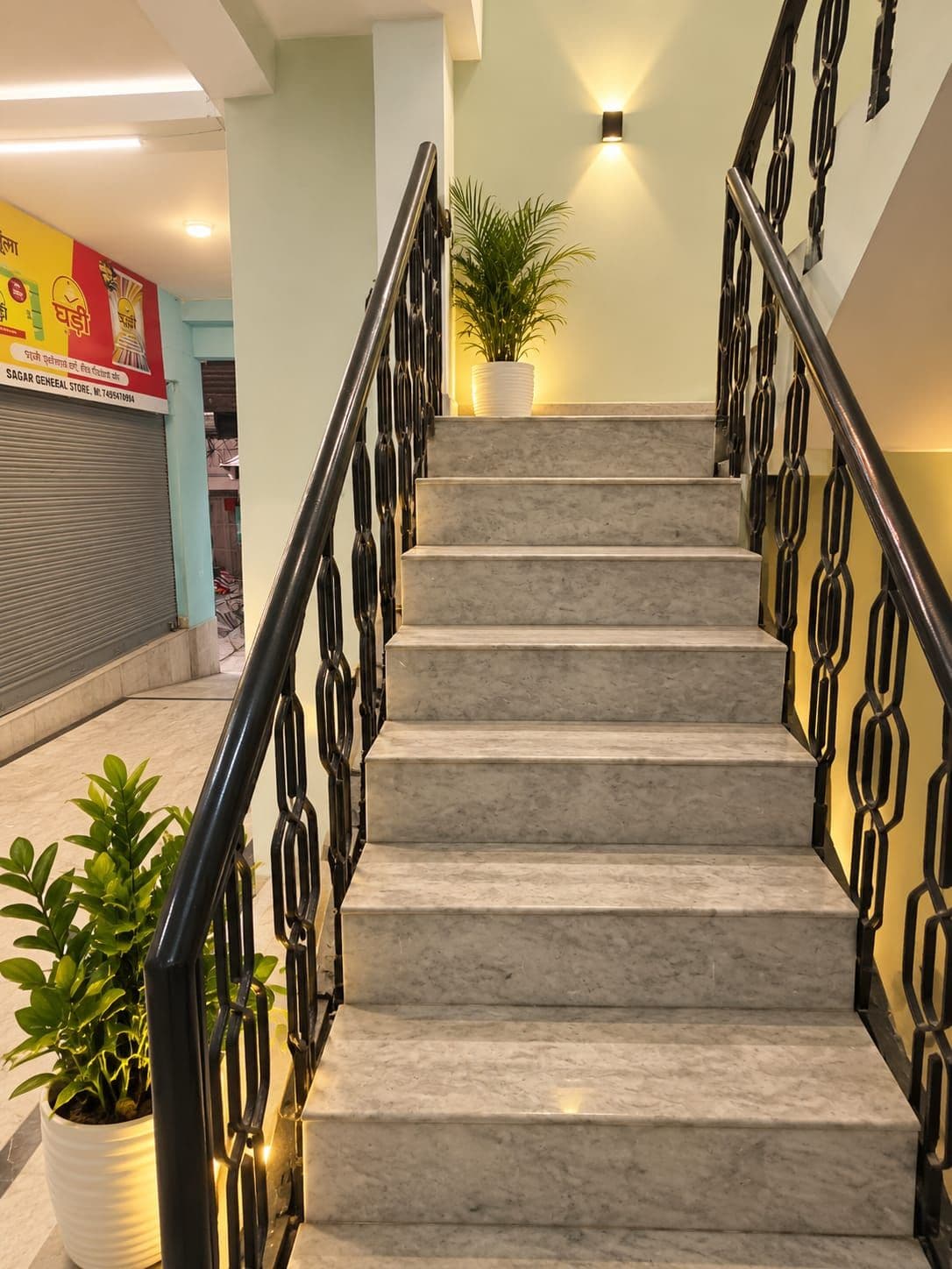 Una escalera de diseño moderno, con barandilla de metal negro y una planta en maceta en la parte superior.