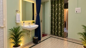 Ein Badezimmer mit Waschbecken, Spiegel und blauer Duschvorhang. Übertöpfe und eine Mülleimer sind ebenfalls vorhanden.
