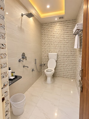 A bathroom with a toilet, shower, and a vanity with toiletries. - Geeta Bhawan Cozy Homestay (Varanasi)
