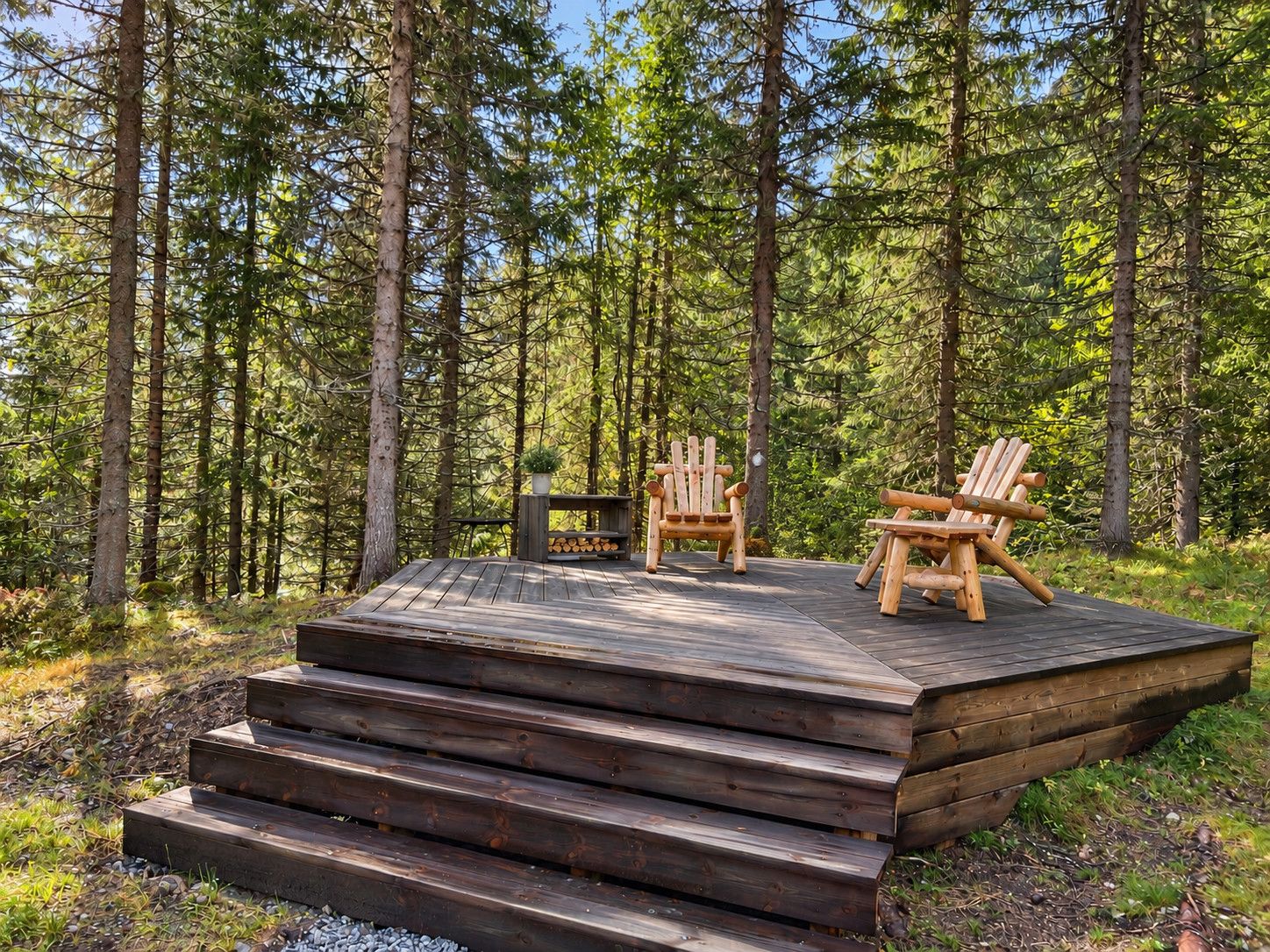 A wooden deck with two Adirondack chairs and a small table, surrounded by a forest.