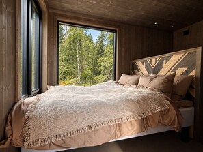 A bedroom with a large window, a bed with a patterned blanket, and a wooden headboard. - Modern and Idyllic Mountain Retreat in Hemsedal (Hemsedal)