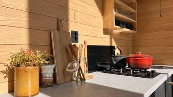 A modern kitchen with wooden panel walls, a countertop, a stove, and various kitchen utensils.
