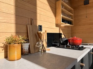 A modern kitchen with wooden panel walls, a countertop, a stove, and various kitchen utensils. - Modern and Idyllic Mountain Retreat in Hemsedal (Hemsedal)