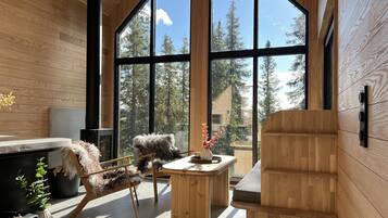 A modern interior with large windows, a fireplace, and wooden furniture.