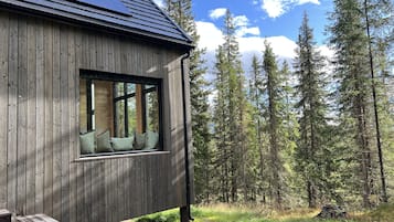 A wooden cabin with a window overlooking a forest.