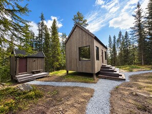A wooden cabin with a small attached shed, surrounded by a forest. - Modern and Idyllic Mountain Retreat in Hemsedal (Hemsedal)