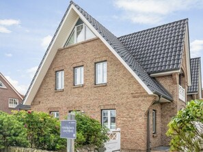 A brick building with a gabled roof and a sign indicating it is the Feriendomizil Lighthouse. - Lighthouse - New, Exclusive, Close to the Beach (Sylt)