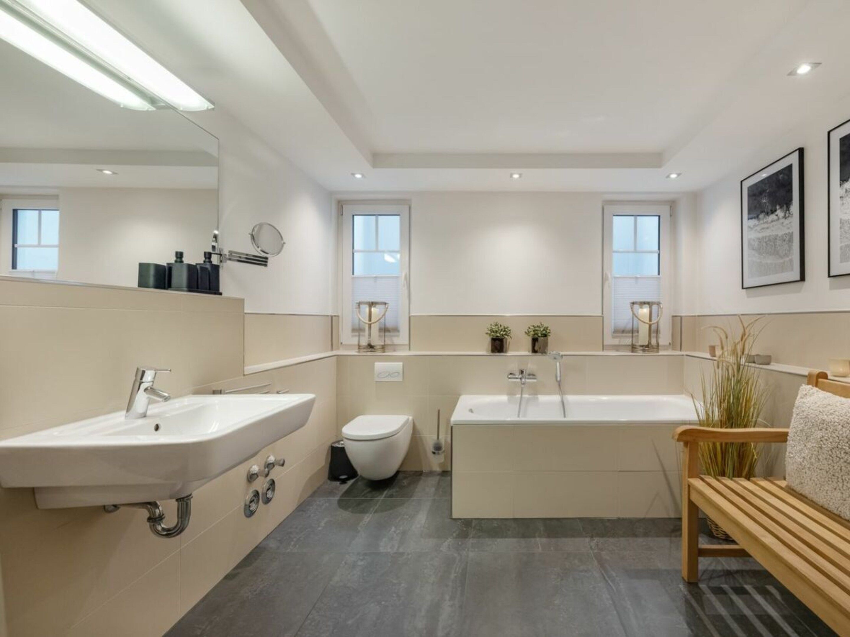 Ein modernes Badezimmer mit einem großen Waschbecken, Toilette, Badewanne und einer Sitzbank.
