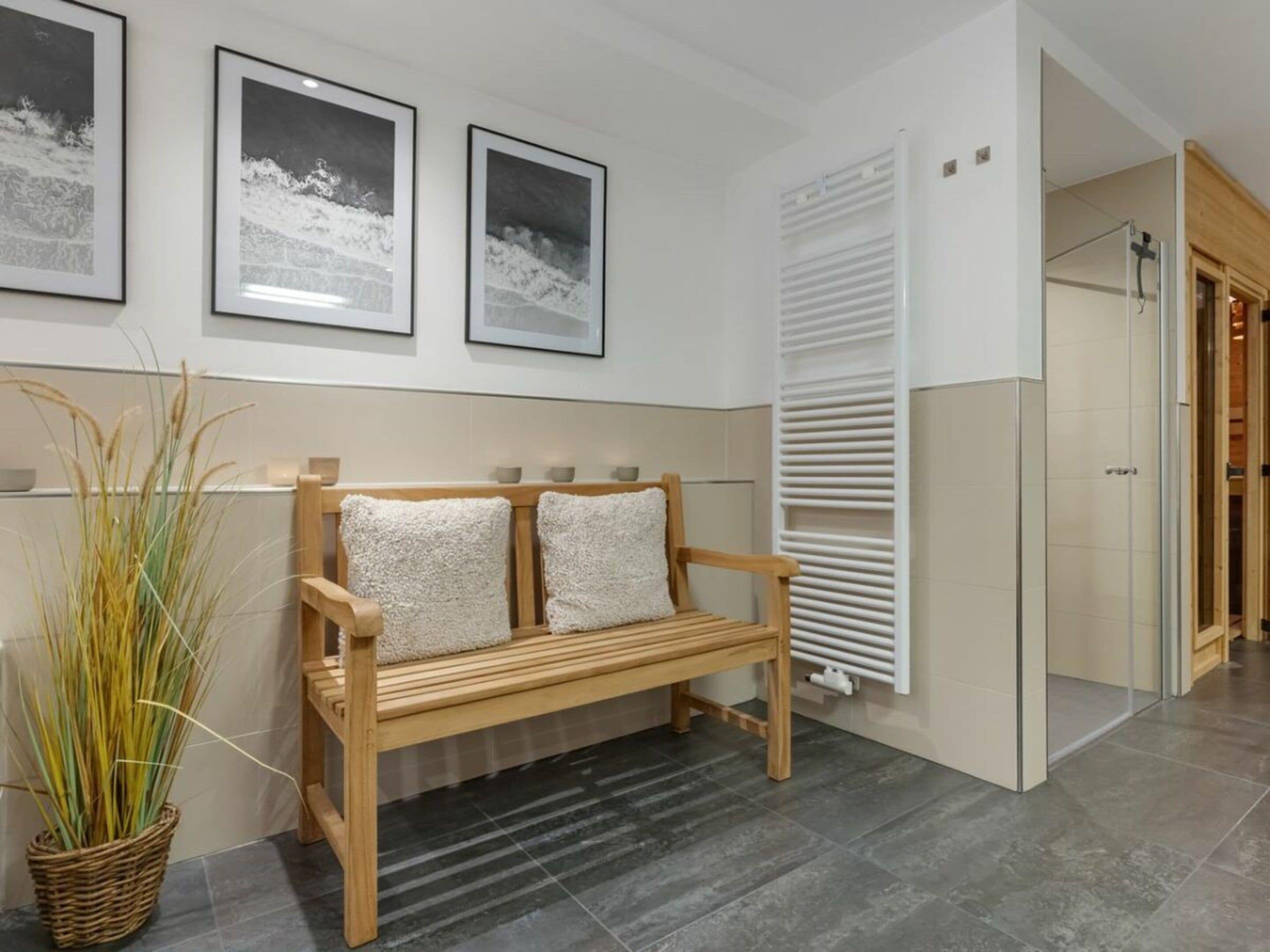 Un banc avec un coussin blanc, un radiateur et un tableau encadré accroché au mur.