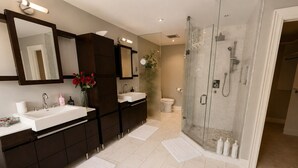 Une salle de bain moderne avec un grand miroir, deux lavabos, une douche et des toilettes.