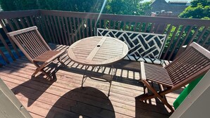 Une terrasse en bois avec une table ronde et deux chaises.